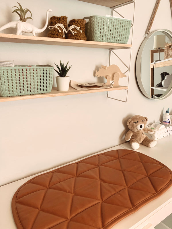 amber color padded quilted vegan leather changing pad shown on a changing table