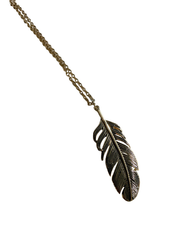 Gold feather pendant necklace on a white surface
