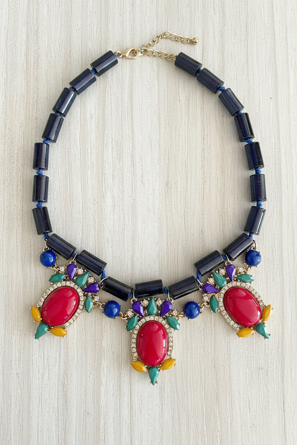 Colorful beaded necklace with red pendants on a dark surface