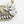 Load image into Gallery viewer, A close-up of a statement necklace featuring a textured antique gold-tone chain and a large floral cluster of clear teardrop rhinestones on a white background.
