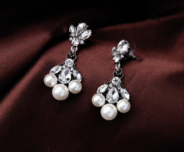 Pearl and crystal drop earrings on a brown fabric background