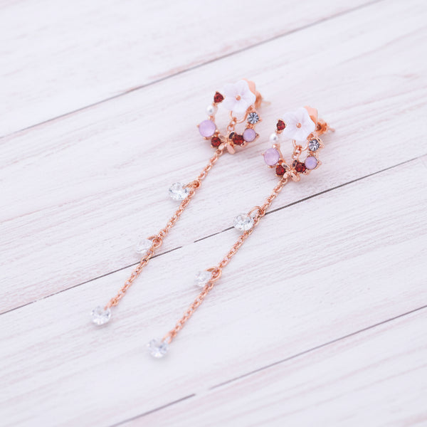 Pair of floral earrings with pink and red accents on a white background