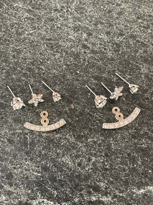 Jewelry items including earrings and a necklace on a textured surface