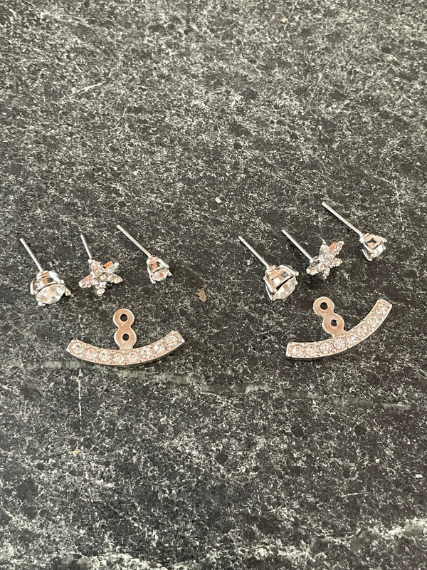 Jewelry items including earrings and a necklace on a textured surface