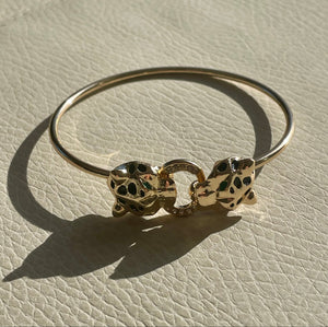 Gold bracelet with heart-shaped charms on a light beige surface