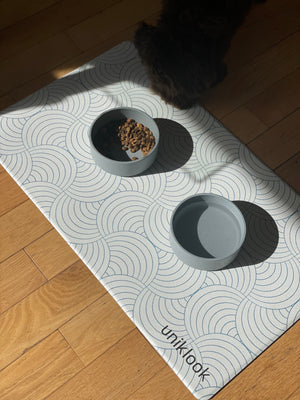 Cat eating from a bowl on a patterned mat with 'unikook' branding.