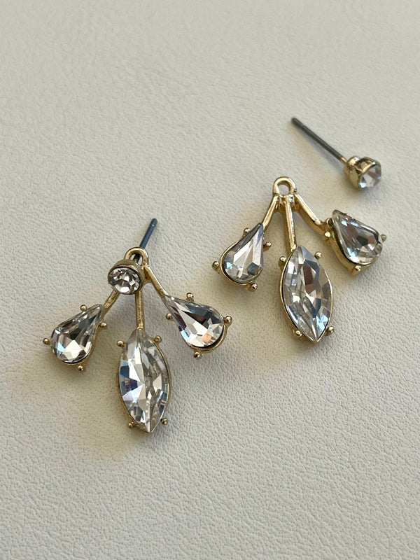 Pair of gold and crystal teardrop earrings on a light gray background