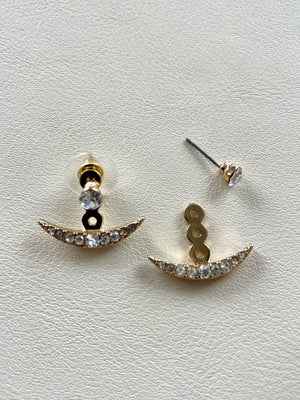 Pair of gold and crystal earrings on a light gray background