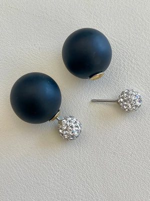 Pair of navy blue spherical earrings with crystal embellishments on a light gray background