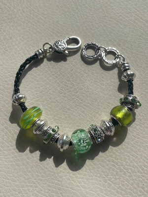 Beaded bracelet with green and silver beads on a textured surface