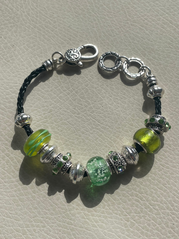 Beaded bracelet with green and silver beads on a textured surface