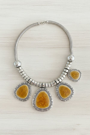 Necklace with yellow stone pendants and silver accents on a dark surface