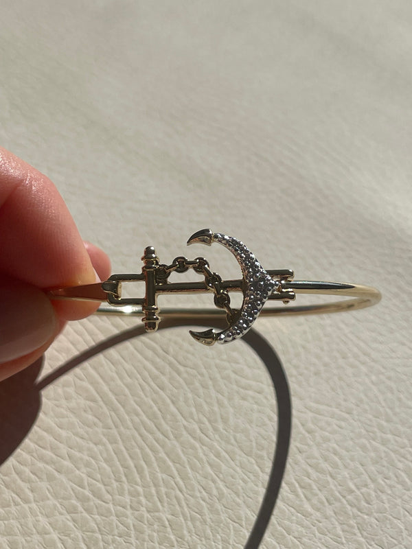 Silver bracelet with intricate design held by a hand against a light background