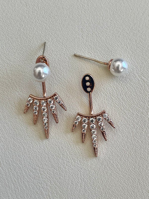 Pair of earrings with pearl and crystal details on a light gray background