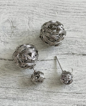 Silver wire ball earrings on a textured wooden surface