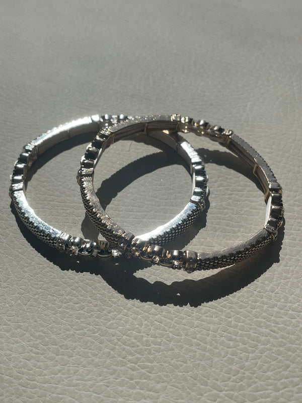 Two silver hoop earrings on a textured gray surface
