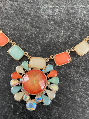 Colorful necklace with large central gemstone on a dark surface