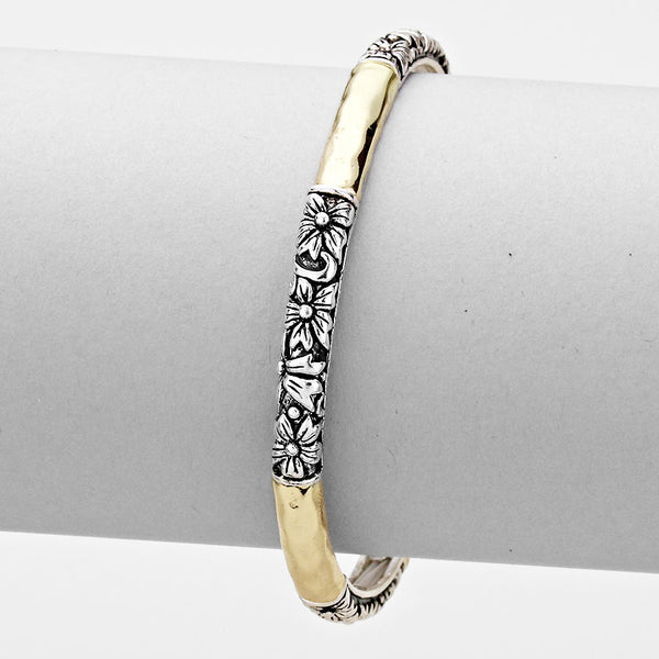 Gold and silver bracelet with intricate design on a gray surface