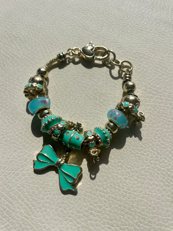 Bracelet with turquoise beads and a bow charm on a light gray background