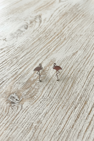 Flamingo earrings on a 'The One' branded card with 'Designed in U.S.A.' text, on a wooden surface.