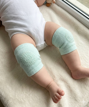 Baby wearing light blue knitted leg warmers on a soft surface