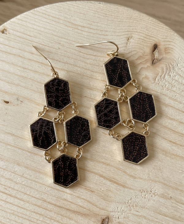 Hexagonal earrings with black stones on a wooden surface
