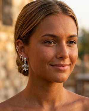 Woman with styled hair and earrings against a blurred outdoor background