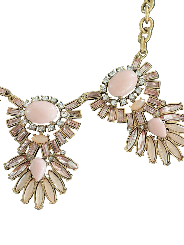 Decorative necklace with pink stones and gold accents on a dark surface