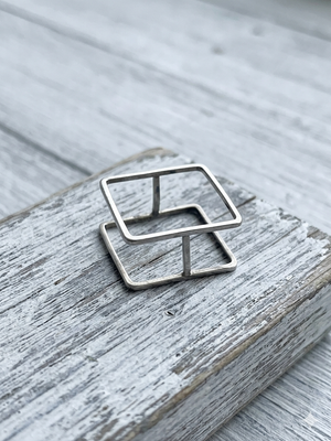 Silver geometric ring on a textured wooden surface