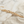 Load image into Gallery viewer, A gold chain bracelet with textured, faceted disc links, styled diagonally across a split background of white marble and light beige sand.
