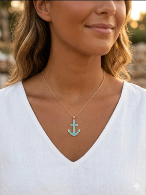 Woman wearing a gold necklace with a turquoise anchor pendant.