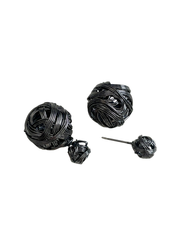 Black yarn ball earrings on a white background