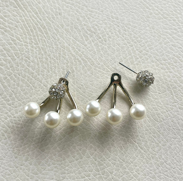 Pair of pearl earrings on a textured white surface