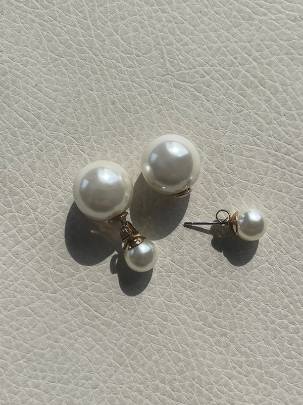 Pearl earrings on a light gray textured surface