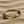 Load image into Gallery viewer, Gold bracelet with arrow designs on a sandy surface
