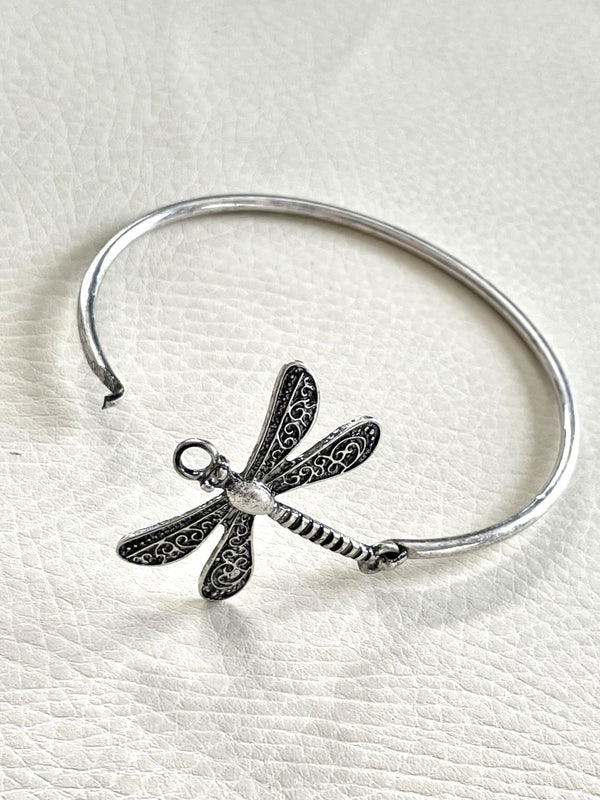 Silver dragonfly charm bracelet on a white textured background