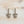 Load image into Gallery viewer, Pair of silver fleur-de-lis earrings on a light wooden surface
