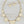 Charger l'image dans la galerie, A gold-tone statement necklace and matching drop earrings with shield-shaped cream enamel pendants, displayed on a dark gray stone surface.
