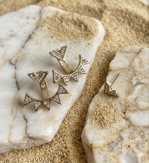 Gold earrings with diamond accents on a marble surface