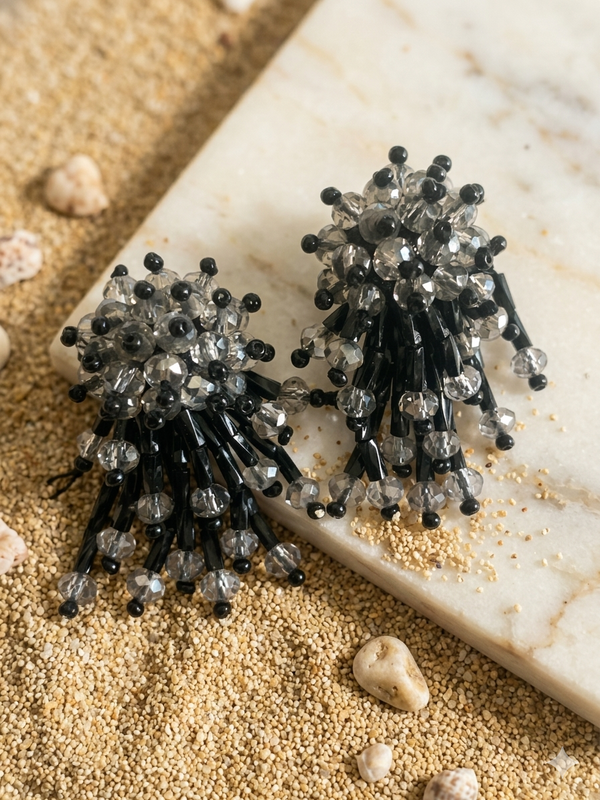 Black and silver beaded earrings on a textured surface