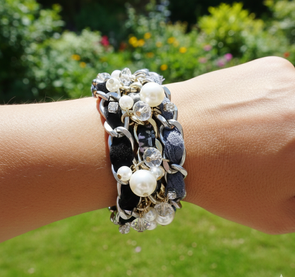 Multibracelet on a wrist with a blurred green outdoor background