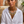 Load image into Gallery viewer, Woman wearing a white shirt and a decorative necklace with potted plants in the background

