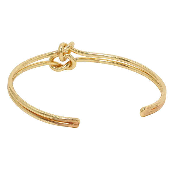 Gold bracelet with a knot design on a light gray background