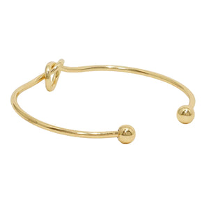 Gold bangle with a small ball on a white background