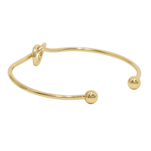 Gold bangle with a small ball on a white background