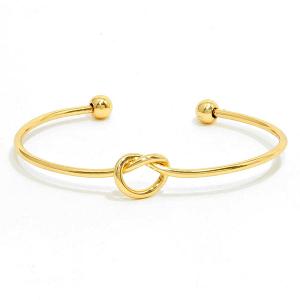 Gold bracelet with a knot design on a white background