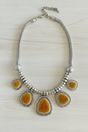 Necklace with yellow and silver circular pendants on a dark surface