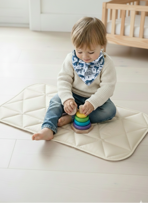 Child playing with colorful stacking toys on a white mat in a room.