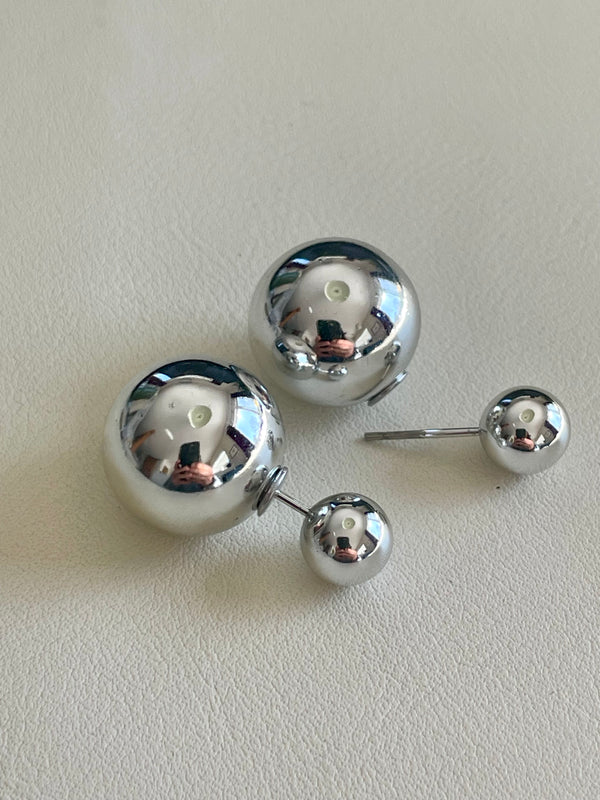 Pair of silver ball earrings on a light gray background
