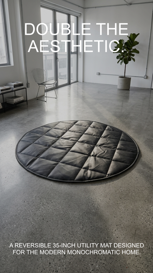 Round gray quilted mat in a modern room with large windows and a plant.